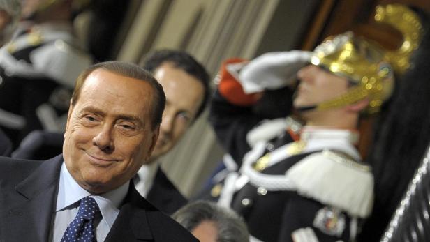 Silvio Berlusconi bei einer Veranstaltung mit einem Gardesoldaten im Hintergrund.