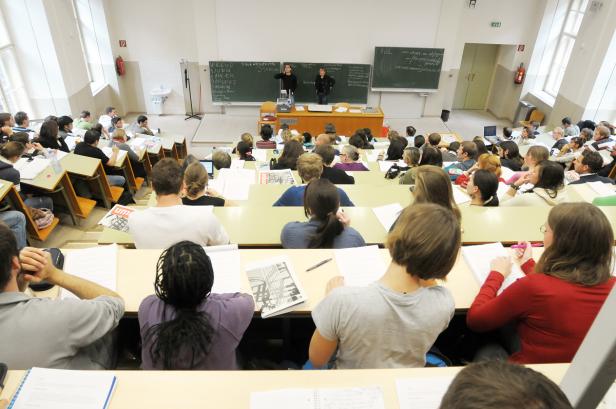 Ein Hörsaal gefüllt mit Studierenden, die einer Vorlesung folgen.