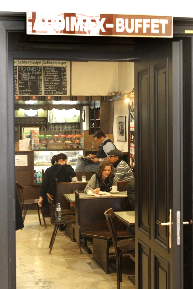 Blick durch eine geöffnete Tür in ein Café mit Gästen an den Tischen.