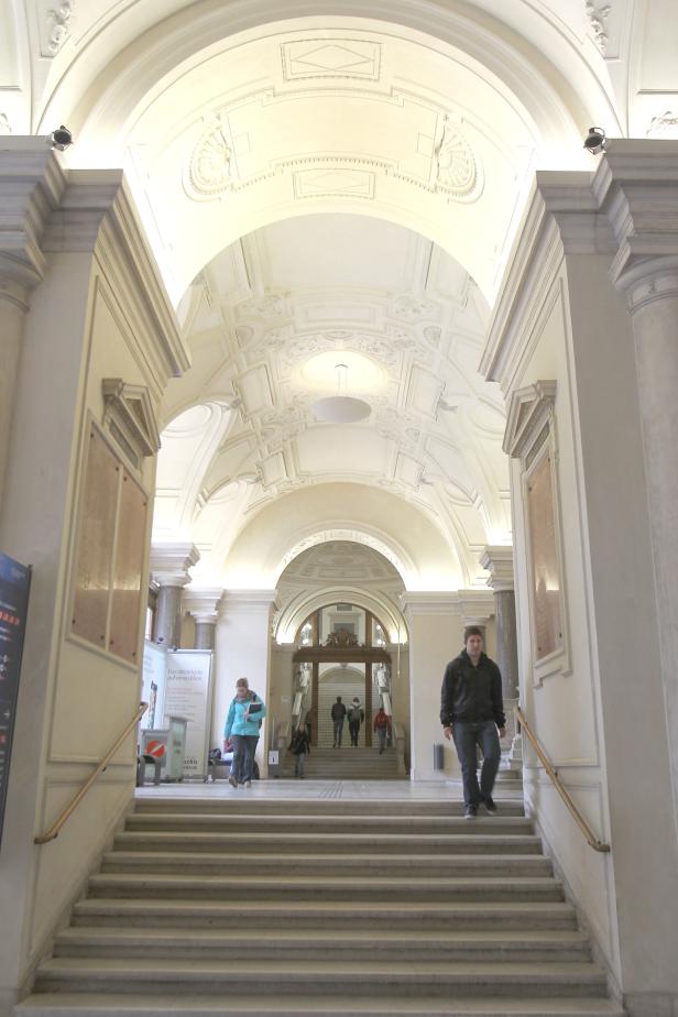 Ein Mann geht eine Treppe in einem Gebäude mit aufwendiger Architektur hinunter.