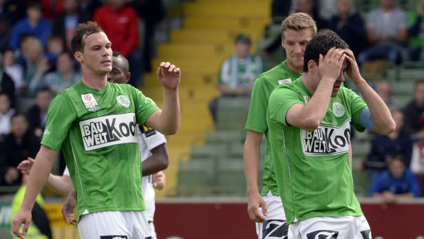 Enttäuschte Fußballspieler in grünen Trikots auf dem Spielfeld.