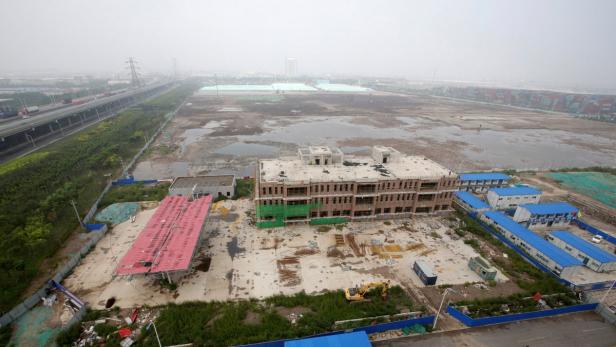 Eine Baustelle mit einem unfertigen Gebäude und Containern an einem trüben Tag.