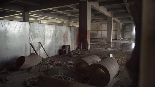 Das Innere eines verlassenen Lagerhauses mit Trümmern und Rohren.