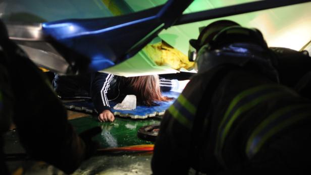 Ein Feuerwehrmann hilft einer Frau, die unter einem Trümmerteil liegt.