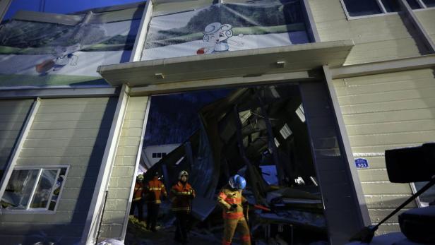 Feuerwehrleute stehen vor einem beschädigten Gebäude mit Maskottchen-Bildern.