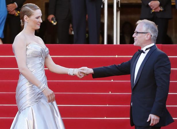 Uma Thurman und Quentin Tarantino halten Hände auf einer roten Treppe.