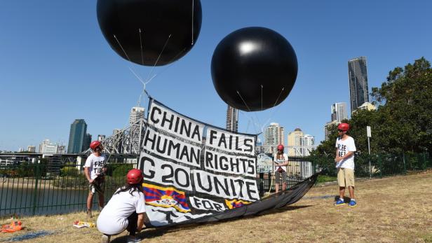 Aktivisten demonstrieren mit einem Banner und schwarzen Ballons gegen Chinas Menschenrechtspolitik.
