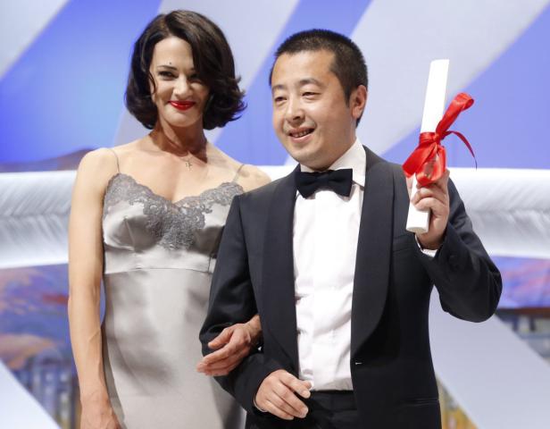 Ein Mann im Smoking hält eine Auszeichnung mit roter Schleife, neben ihm eine Frau im Abendkleid.