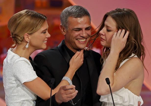 Ein Mann wird von zwei Frauen umarmt, eine lächelt, die andere weint.