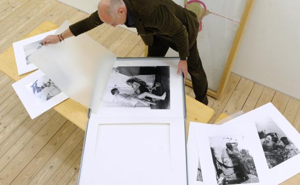 Ein Mann betrachtet Schwarz-Weiß-Fotografien auf einem Tisch.