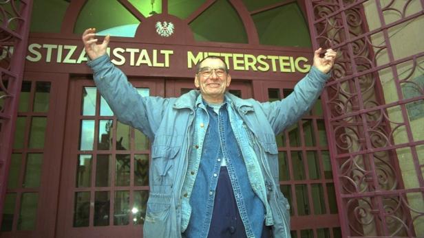 Ein älterer Mann steht mit erhobenen Armen vor der Justizanstalt Mittersteig in Wien.