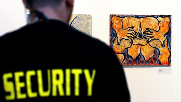 Ein Wachmann steht vor einem abstrakten Gemälde in einer Kunstgalerie.