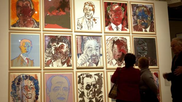 Besucher betrachten eine Wand mit Porträtgemälden in einer Kunstgalerie.