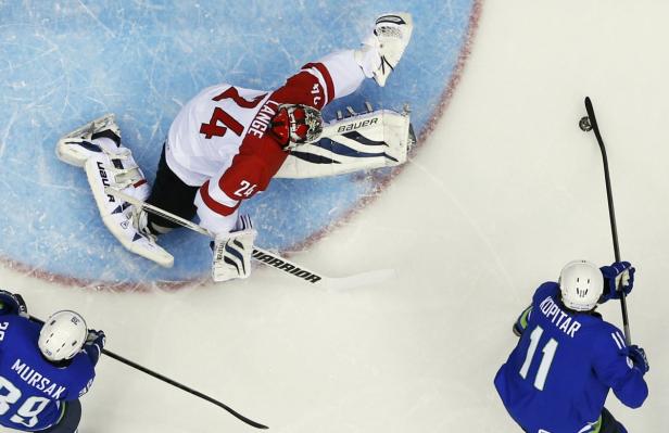 Ein Eishockeytorwart wehrt einen Schuss von Anže Kopitar ab, während ein weiterer Spieler zusieht.