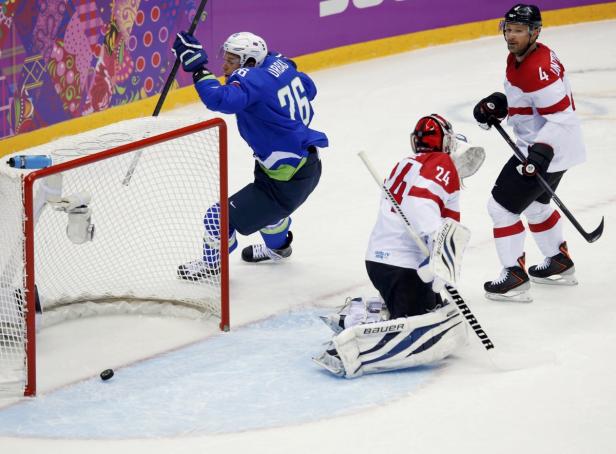 Ein Eishockeyspieler erzielt ein Tor, während der Torwart auf dem Eis kniet.