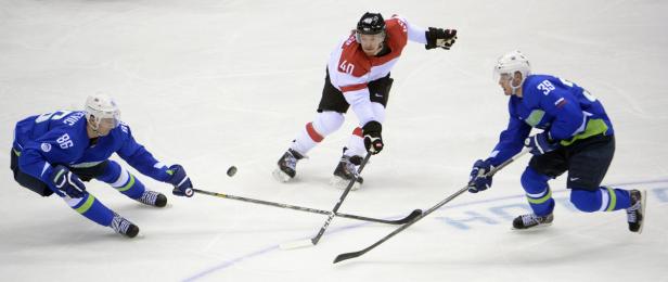 Drei Eishockeyspieler kämpfen um den Puck auf dem Eis.