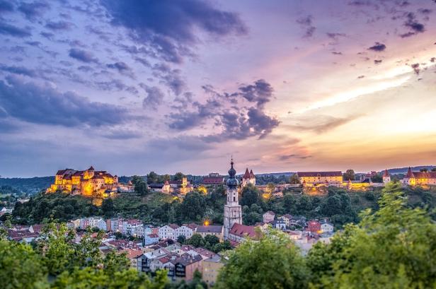 Das hübsche Städtchen Burghausen in der Abendsonne - darüber thront eine lange Burg.
