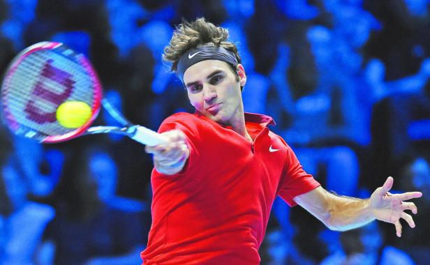 Roger Federer bei einem Tennismatch in rotem Hemd und Stirnband.