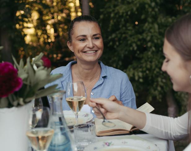 Zwei Frauen sitzen an einem Tisch im Freien und genießen eine Mahlzeit.