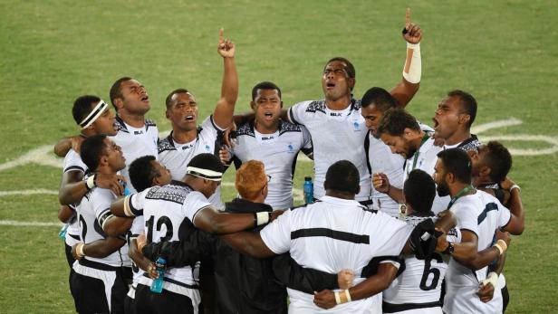 Das Rugby-Team von Fidschi feiert einen Sieg mit erhobenen Armen.