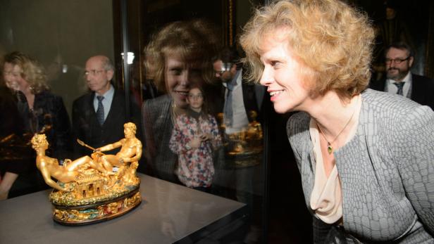 Eine Frau betrachtet eine goldene Skulptur von Neptun und Amphitrite in einem Museum.