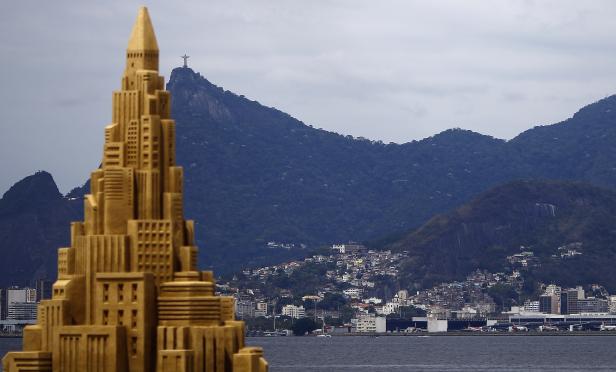 Eine Sandburg in Wolkenkratzerform vor der Skyline von Rio de Janeiro mit der Christusstatue.
