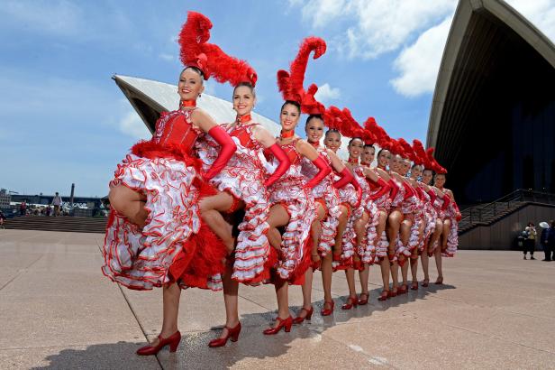 Eine Gruppe von Tänzerinnen in roten Kostümen vor dem Opernhaus von Sydney.