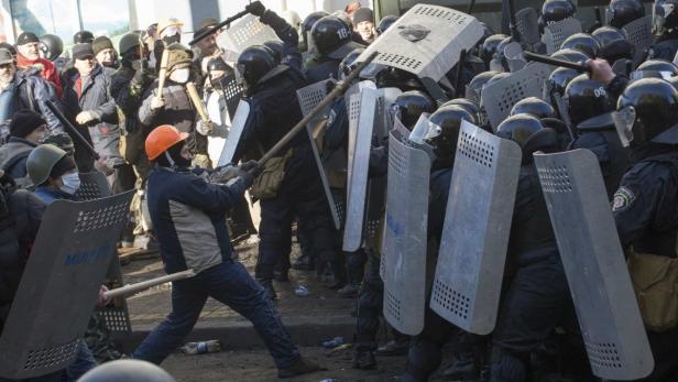 Bei einer Demonstration stehen sich Demonstranten und Polizisten mit Schilden gegenüber.