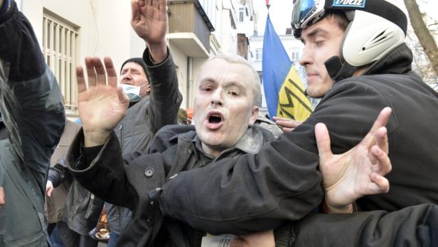 Ein Mann wird während einer Demonstration von einer anderen Person zurückgehalten.
