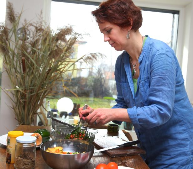 Eine Frau mit roten Haaren bereitet in einer Küche einen Salat zu.