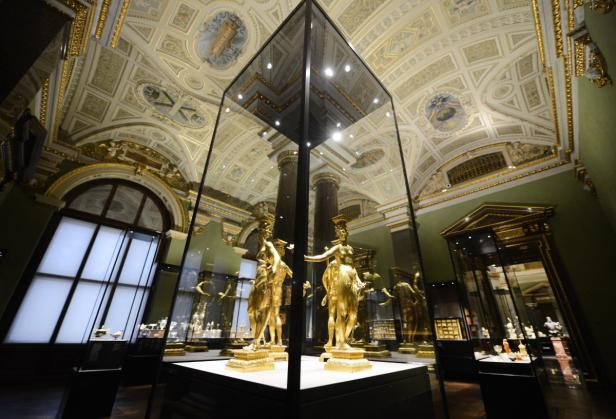 Goldene Statuen in einer Vitrine in einem prunkvollen Museumssaal.