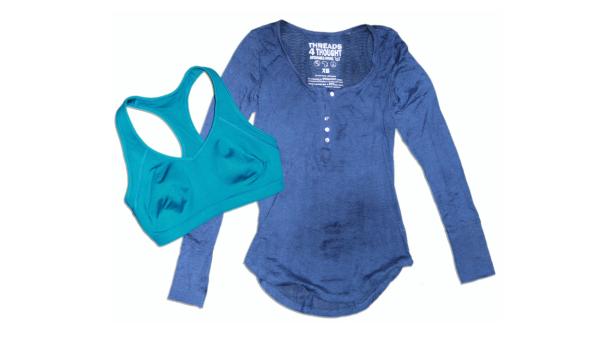 Ein blaues Langarmshirt und ein türkisfarbener Sport-BH liegen auf einem weißen Hintergrund.