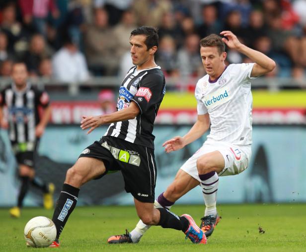 Zwei Fußballspieler kämpfen um den Ball auf dem Spielfeld.