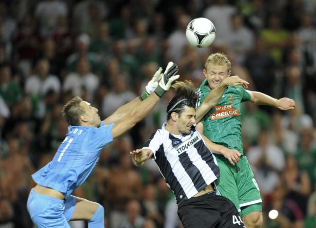 Drei Fußballspieler kämpfen um den Ball während eines Spiels.