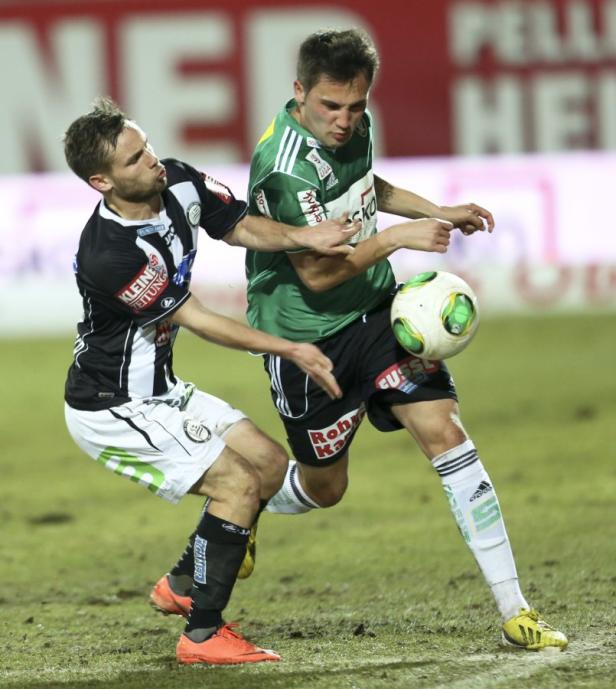 Zwei Fußballspieler kämpfen um den Ball während eines Spiels.