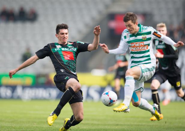 Zwei Fußballspieler kämpfen um den Ball auf dem Spielfeld.