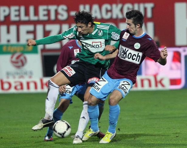 Zwei Fußballspieler kämpfen um den Ball während eines Spiels.
