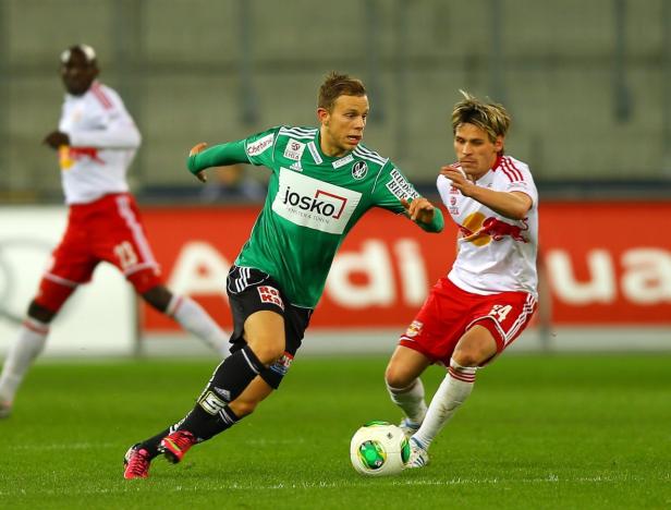 Zwei Fußballspieler kämpfen um den Ball auf dem Spielfeld.