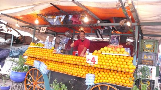 Ein Mann verkauft Orangen von einem dekorierten Stand in Marrakesch.