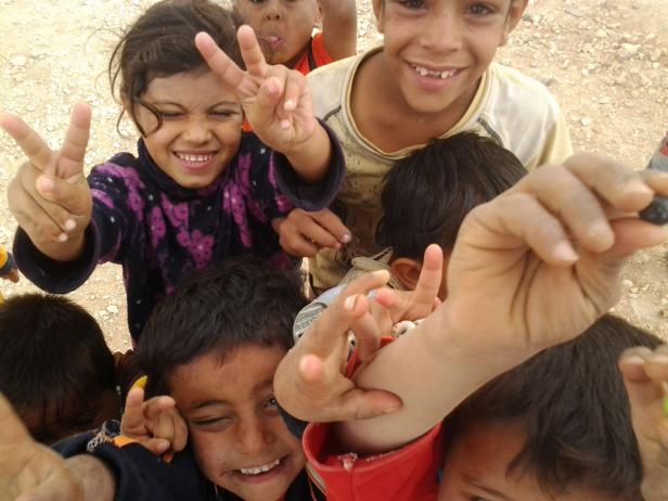 Eine Gruppe lachender Kinder zeigt Victory-Zeichen in die Kamera.