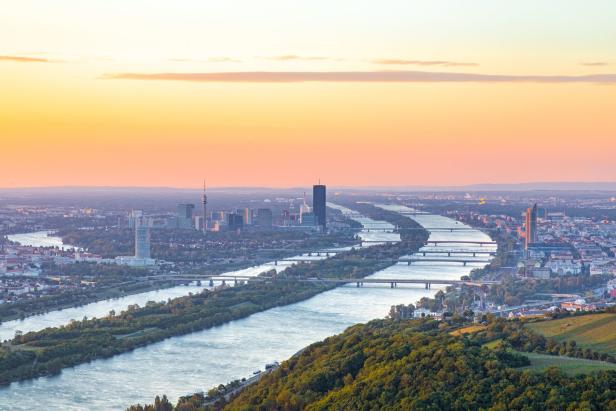 Blick auf Wien mit der Donau und der Skyline bei Sonnenuntergang.