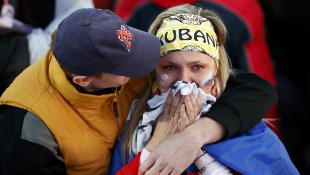 Eine weinende Frau mit russischer Flagge und „Kuban“-Stirnband wird von einem Mann getröstet.