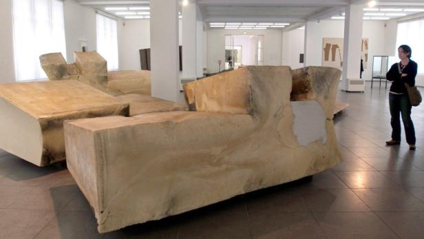 Eine Frau betrachtet eine große, abstrakte Skulptur in einer Kunstgalerie.