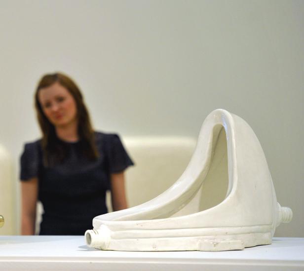Eine Frau betrachtet „Fountain“ von Marcel Duchamp, ein Urinal als Kunstwerk.