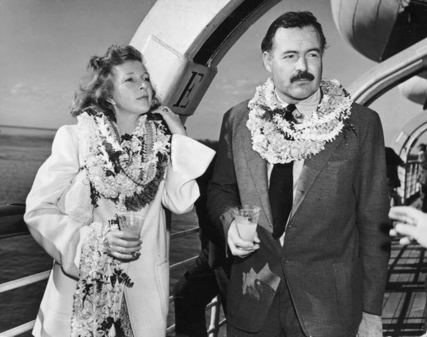 Ernest Hemingway und Martha Gellhorn mit Blumenkränzen an Bord eines Schiffes.