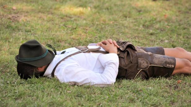 Ein Mann in Tracht liegt auf einer Wiese.