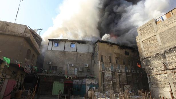 Dichter Rauch steigt zwischen Gebäuden in einer Stadt auf.