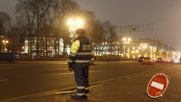 Ein Verkehrspolizist steht nachts an einer belebten Straße mit einem Stoppschild.