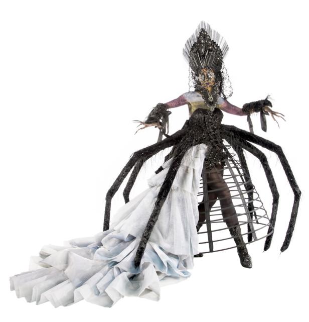 Eine Person in einem extravaganten Spinnenkostüm mit Krone und Schleppe.