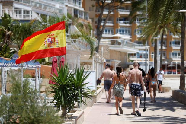 Ein sonniger Tag an einer Strandpromenade mit der spanischen Flagge im Vordergrund.